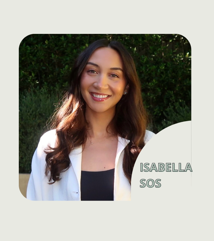 Portrait of Isabella SOS smiling outdoors, wearing a white blazer over a black top, with green bushes behind; name overlay in bottom-right.